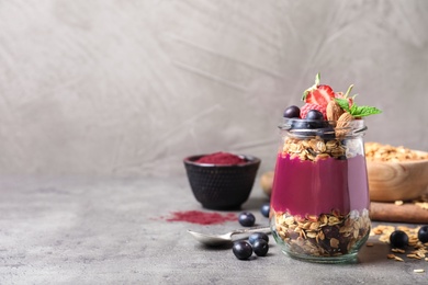 Photo of Delicious acai dessert with granola and berries served on grey table. Space for text
