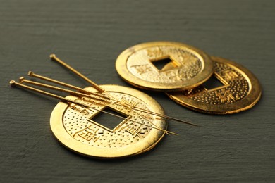 Photo of Acupuncture needles and antique Chinese coins on grey wooden table, closeup