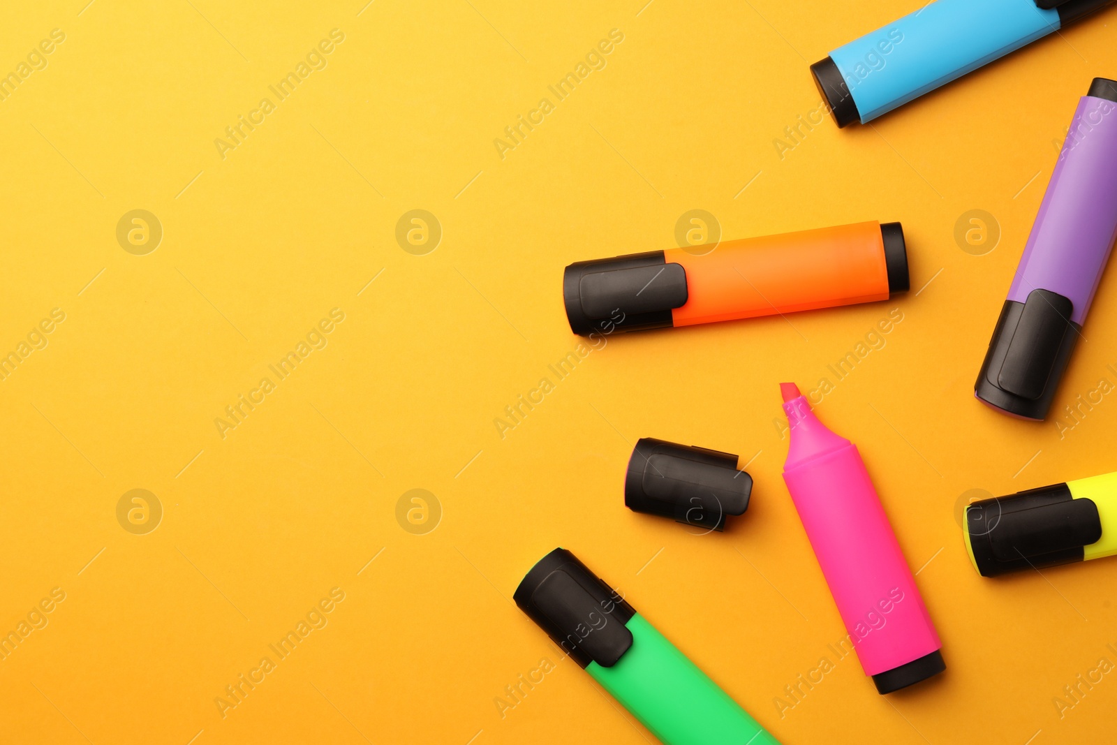Photo of Bright markers on orange background, flat lay. Space for text