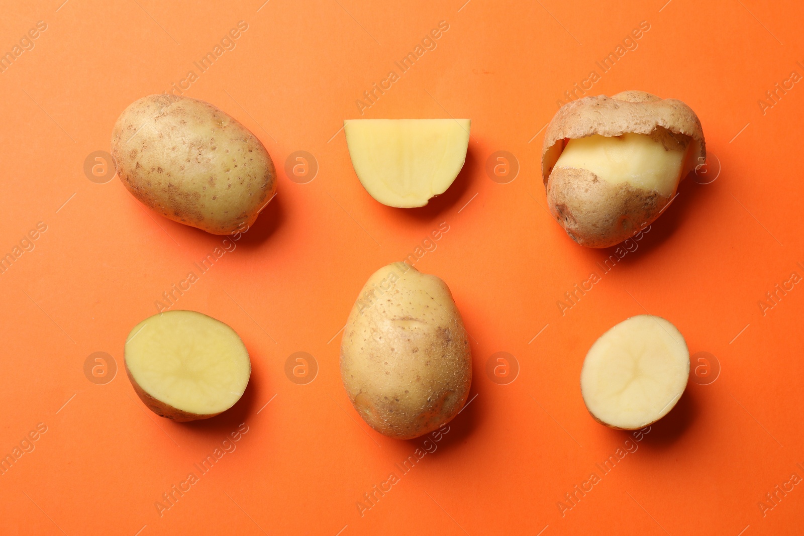 Photo of Fresh raw potatoes on orange background, flat lay