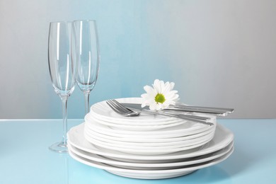 Set of clean dishes, glasses and cutlery on light blue table