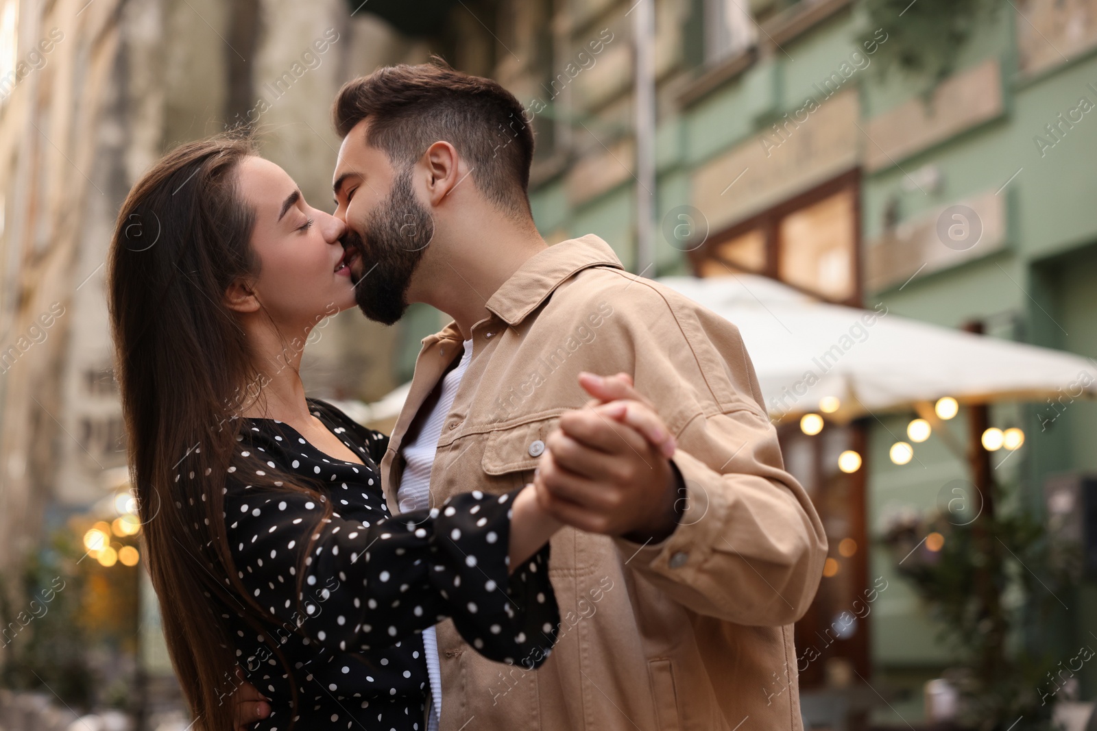 Photo of Lovely couple kissing and dancing together on city street