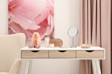 Dressing table with mirror, cosmetic products, jewelry and burning candles in makeup room