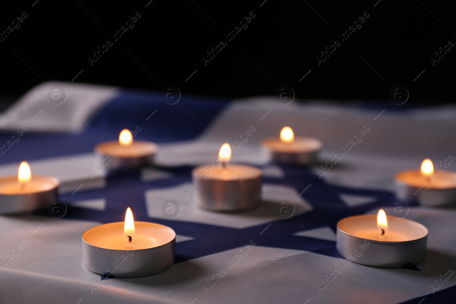 Photo of Burning candles on flag of Israel. Holocaust memory day