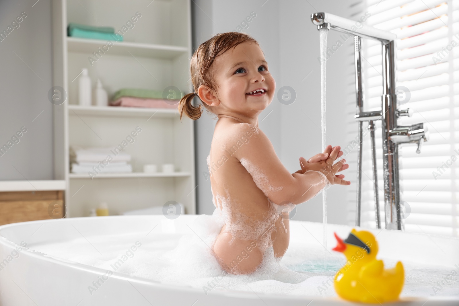 Photo of Cute little girl in foamy bath at home