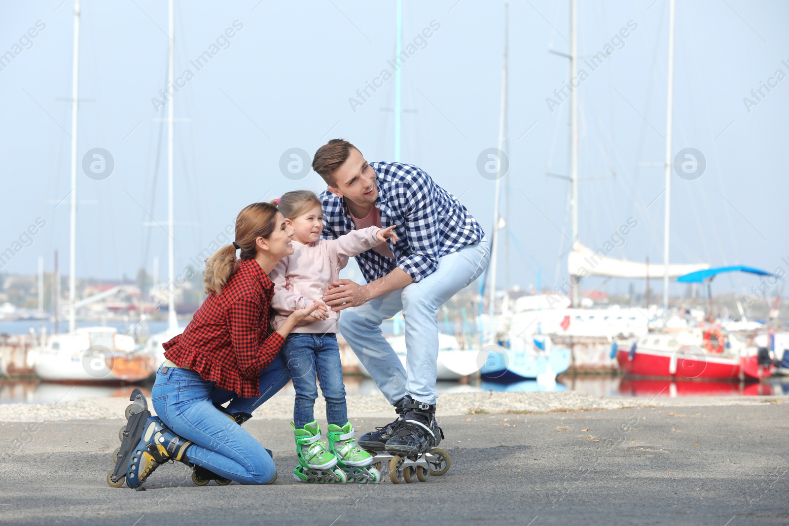 Photo of Happy family wearing roller skates on embankment