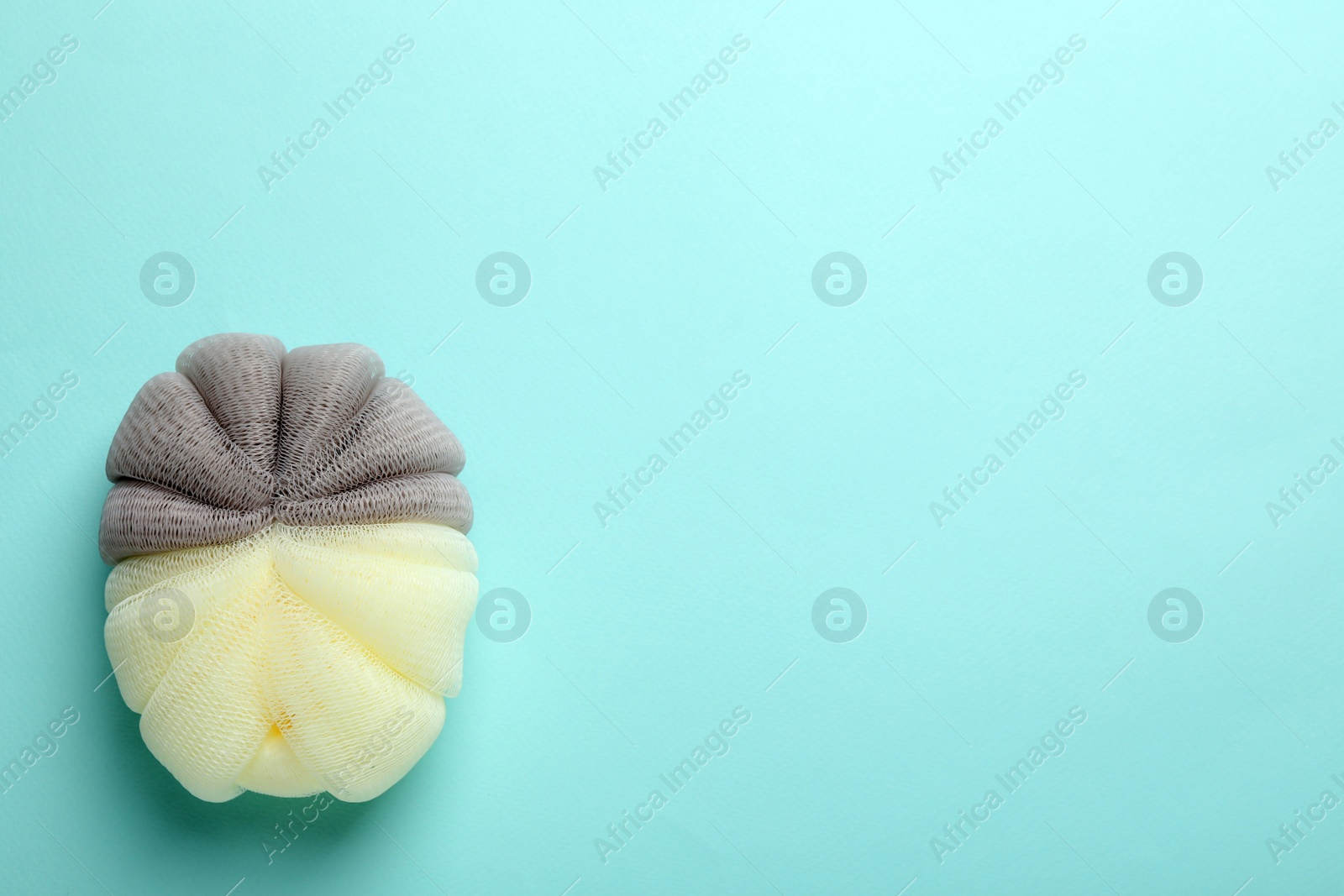 Photo of New bath sponge on light blue background, top view. Space for text