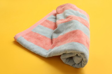 Photo of Rolled striped beach towel on yellow background