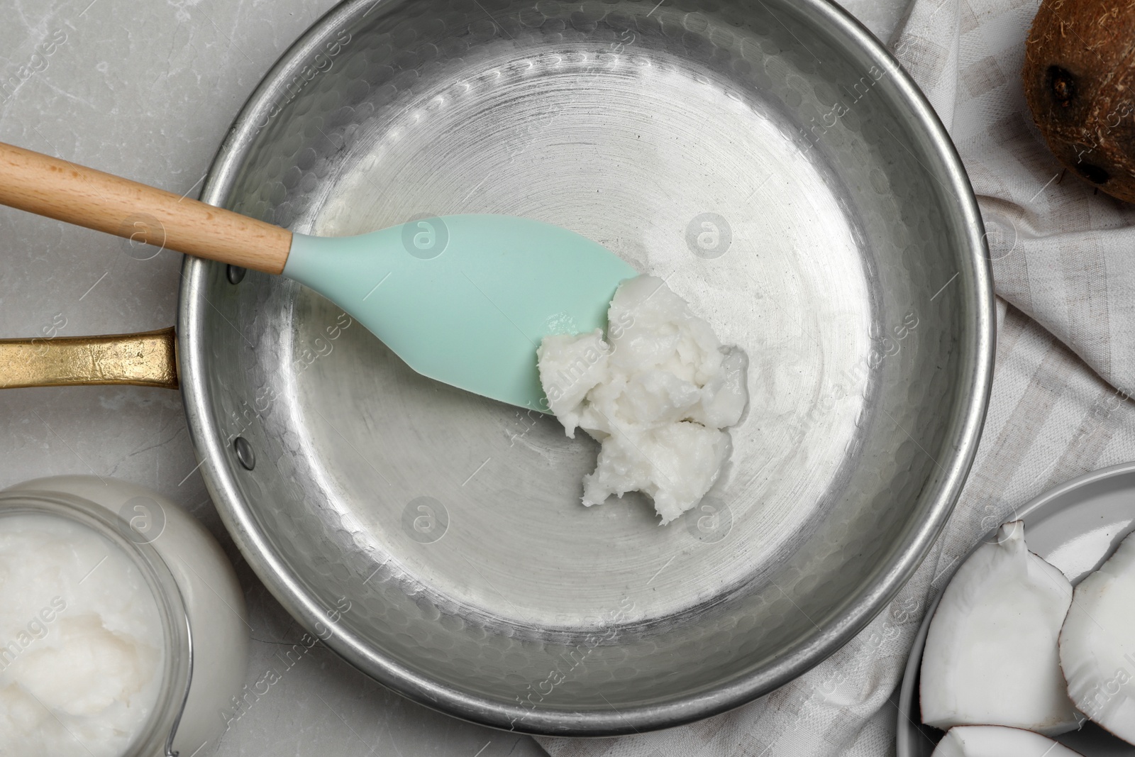 Photo of Frying pan with coconut oil and spatula on light grey table, flat lay