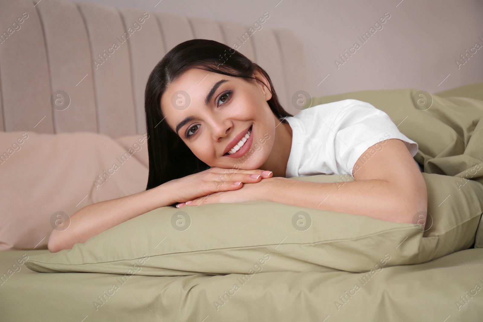 Photo of Woman lying in comfortable bed with green linens