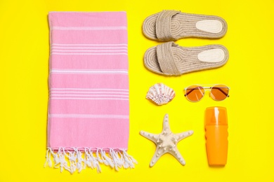 Photo of Flat lay composition with beach accessories on yellow background