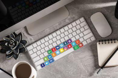 MYKOLAIV, UKRAINE - APRIL 30, 2020: Computer keyboard with social media apps logotypes on marble table, flat lay
