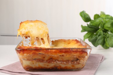 Delicious lasagna in baking dish on white table