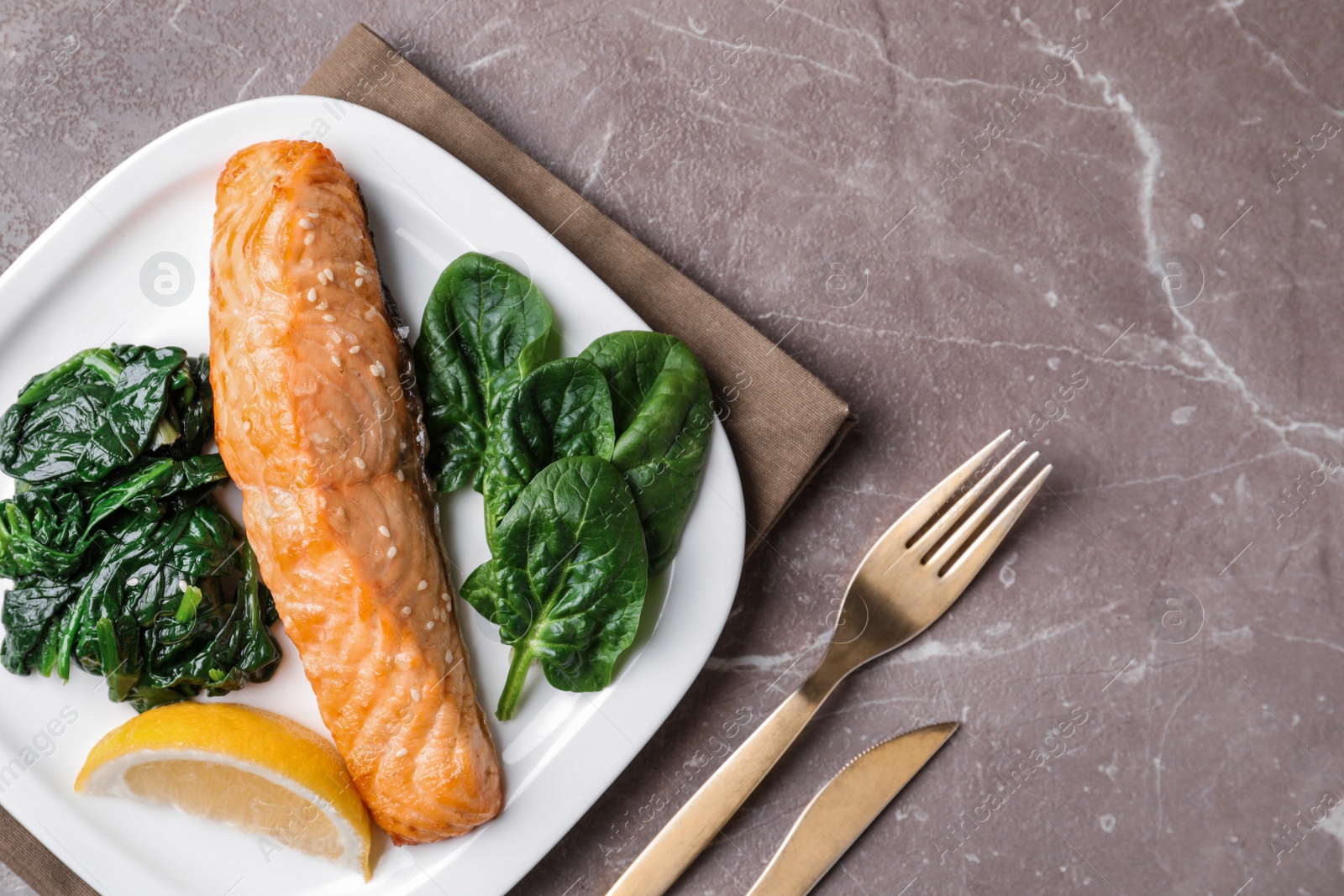 Photo of Tasty salmon with spinach and lemon served on marble table, flat lay