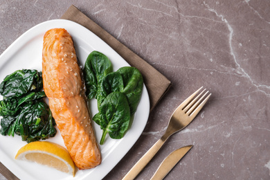 Photo of Tasty salmon with spinach and lemon served on marble table, flat lay