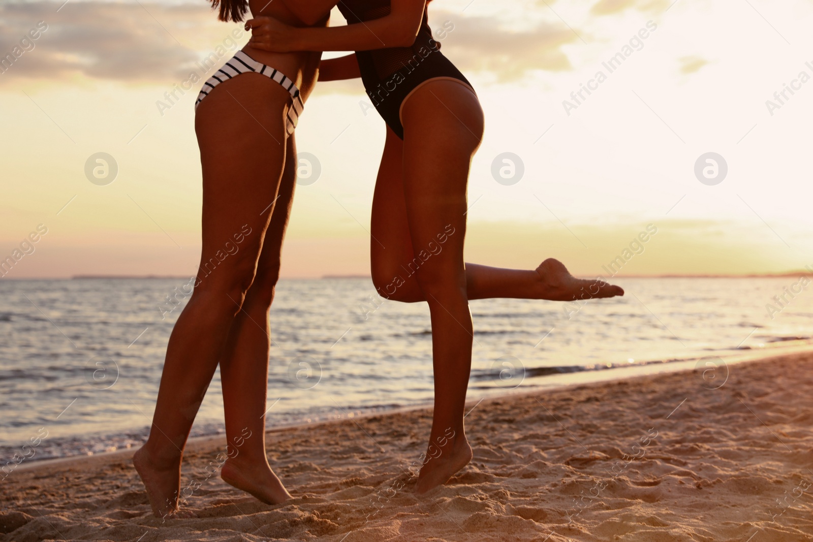 Photo of Young woman in bikini with girlfriend on beach, closeup. Lovely couple