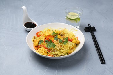 Photo of Stir-fry. Delicious cooked noodles with chicken and vegetables in bowl served on gray textured table