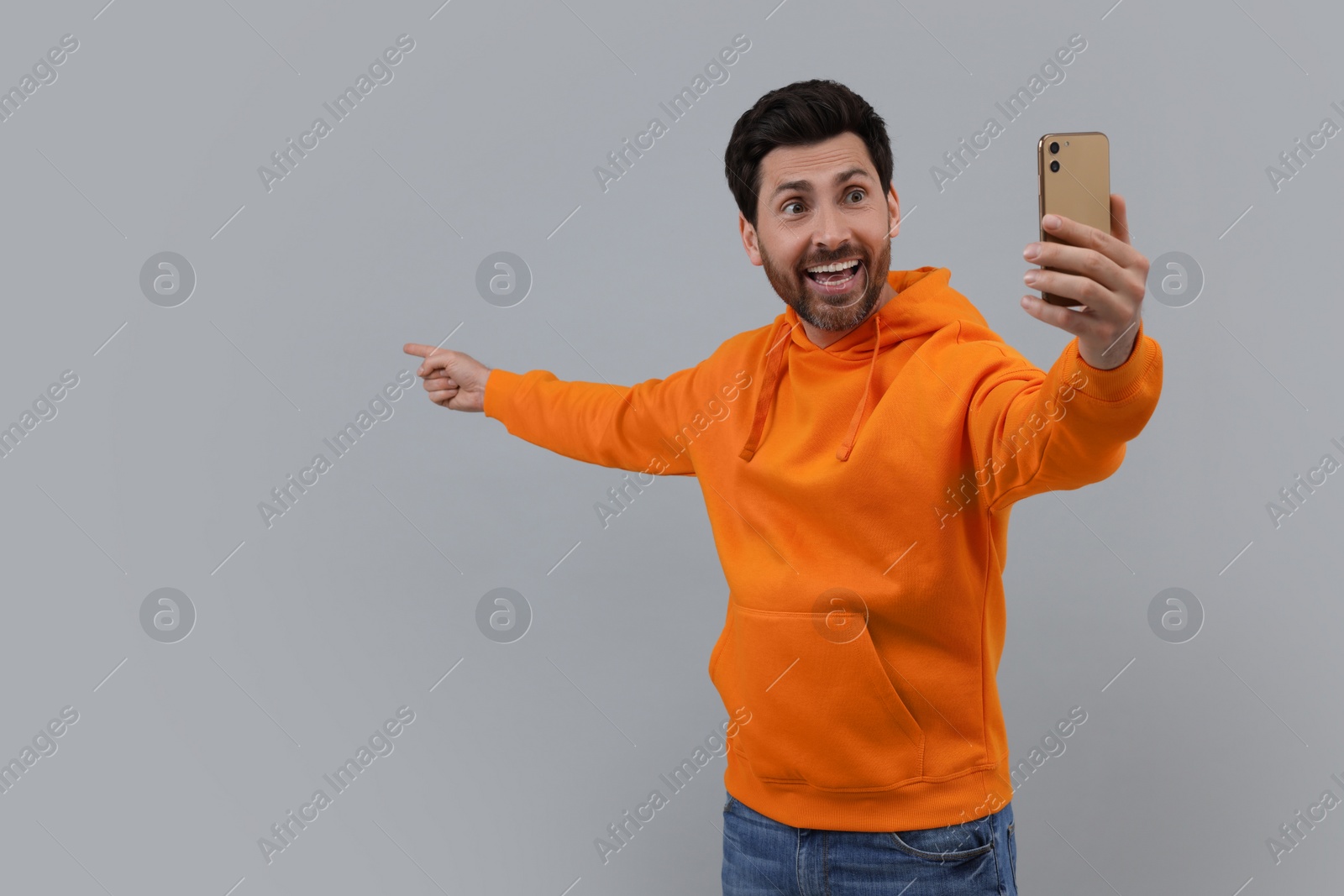 Photo of Smiling man taking selfie with smartphone on grey background, space for text