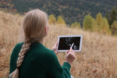 Photo of Young woman drawing on tablet outdoors, back view