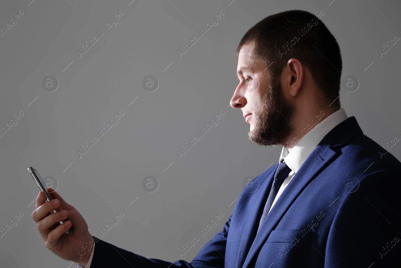 Photo of Man unlocking smartphone with facial scanner on grey background. Biometric verification