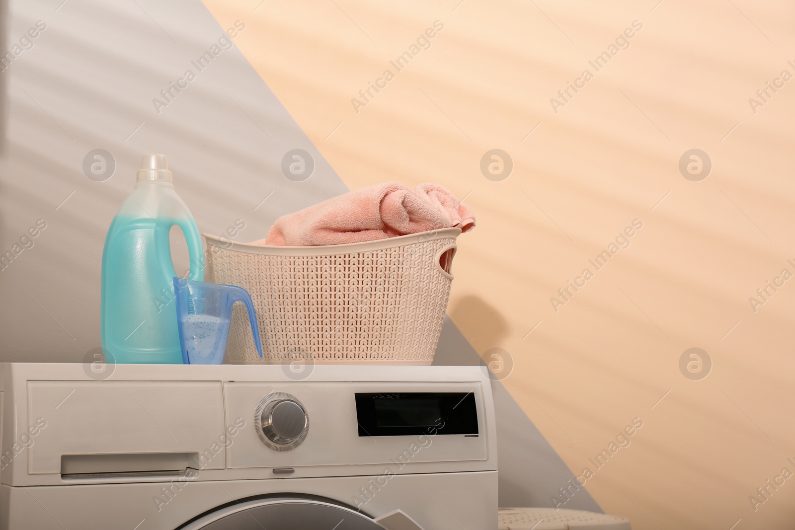 Photo of Detergents and laundry basket on washing machine indoors. Space for text
