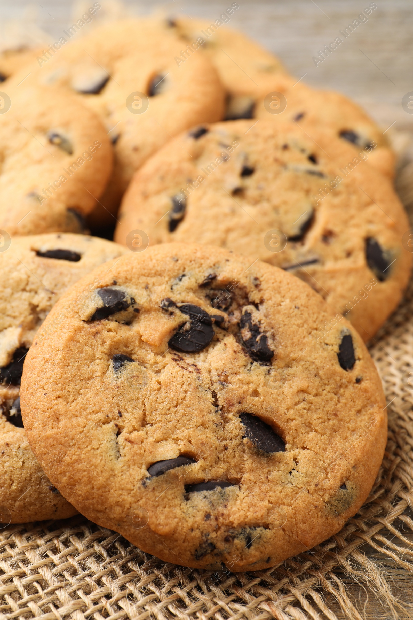 Photo of Delicious chocolate chip cookies on burlap fabric, closeup