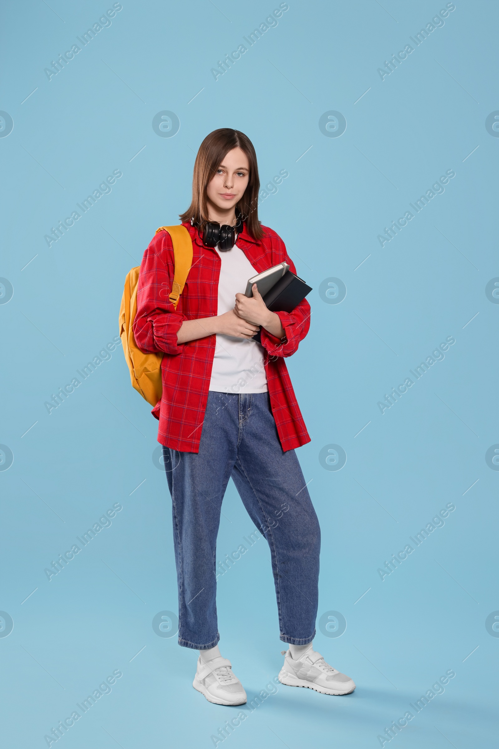 Photo of Beautiful teenage girl with books on light blue background