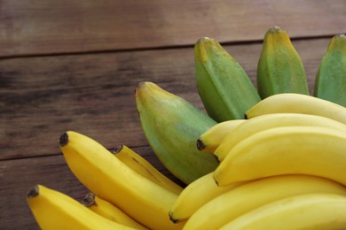 Photo of Bunches of tasty bananas on wooden table, closeup