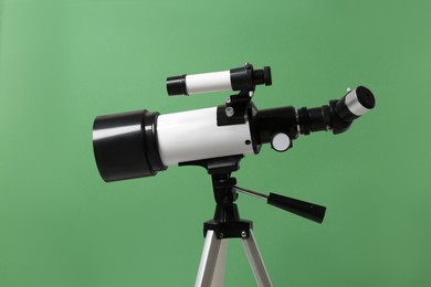 Photo of Tripod with modern telescope on green background, closeup
