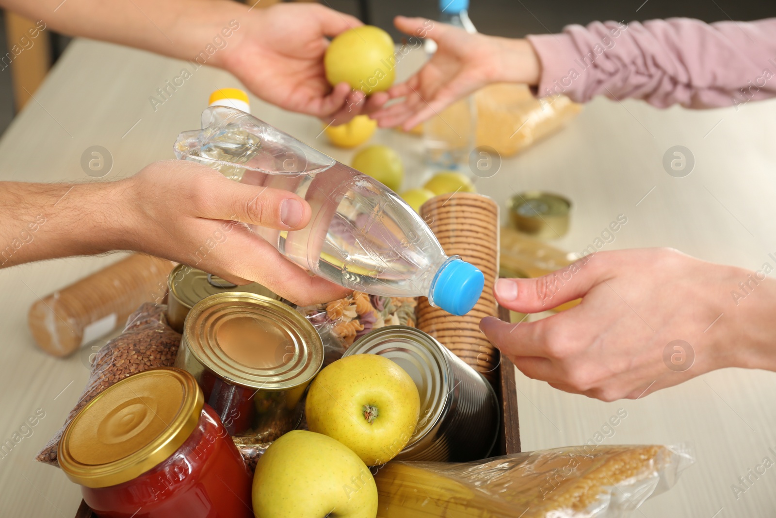 Photo of Volunteers taking food out of donation box on table, closeup