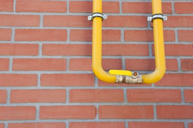 Photo of Yellow gas pipe on red brick wall outdoors, space for text