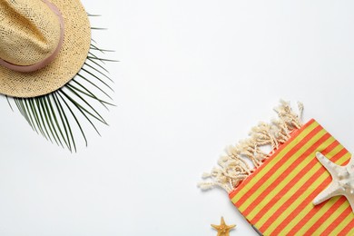 Beach towel and straw hat on white background, flat lay. Space for text