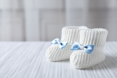 Handmade baby booties on plaid against blurred background. Space for text