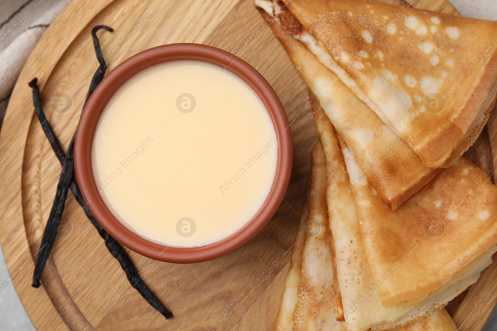 Photo of Tasty crepes served with condensed milk on table, flat lay