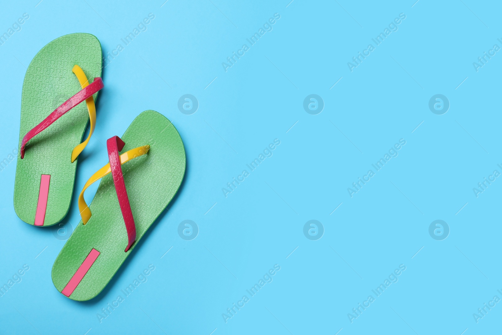 Photo of Stylish flip flops on light blue background, flat lay. Space for text