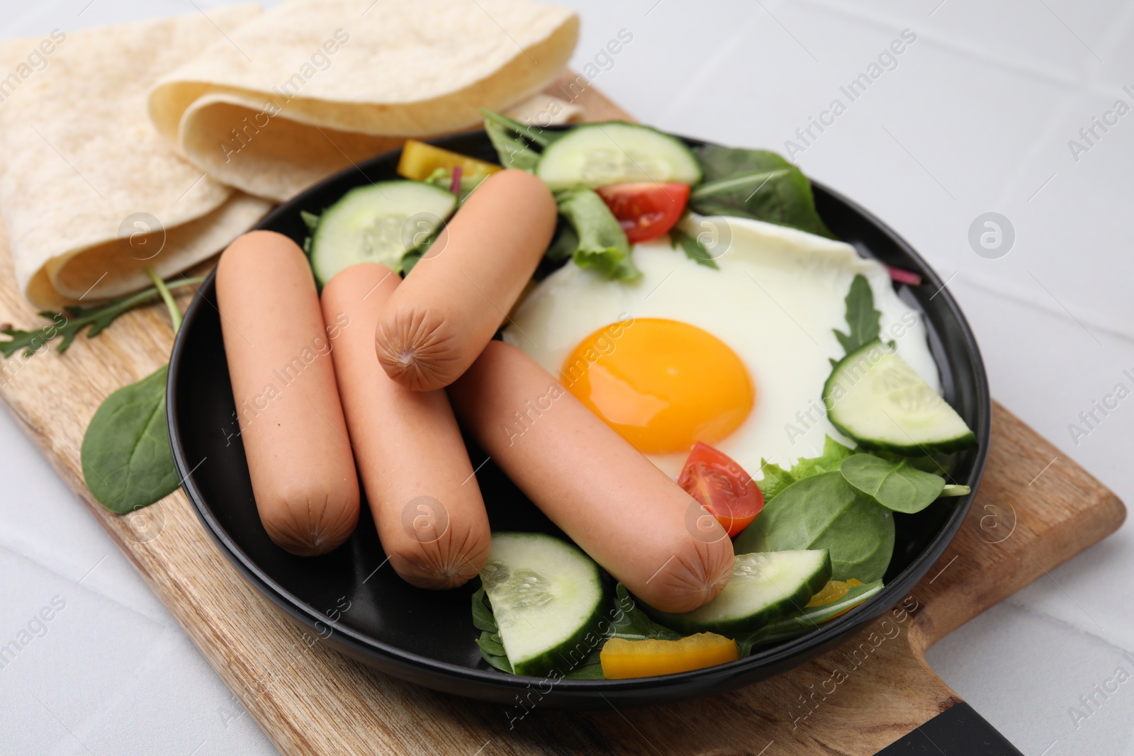 Photo of Delicious breakfast with boiled sausages and fried egg on white tiled table