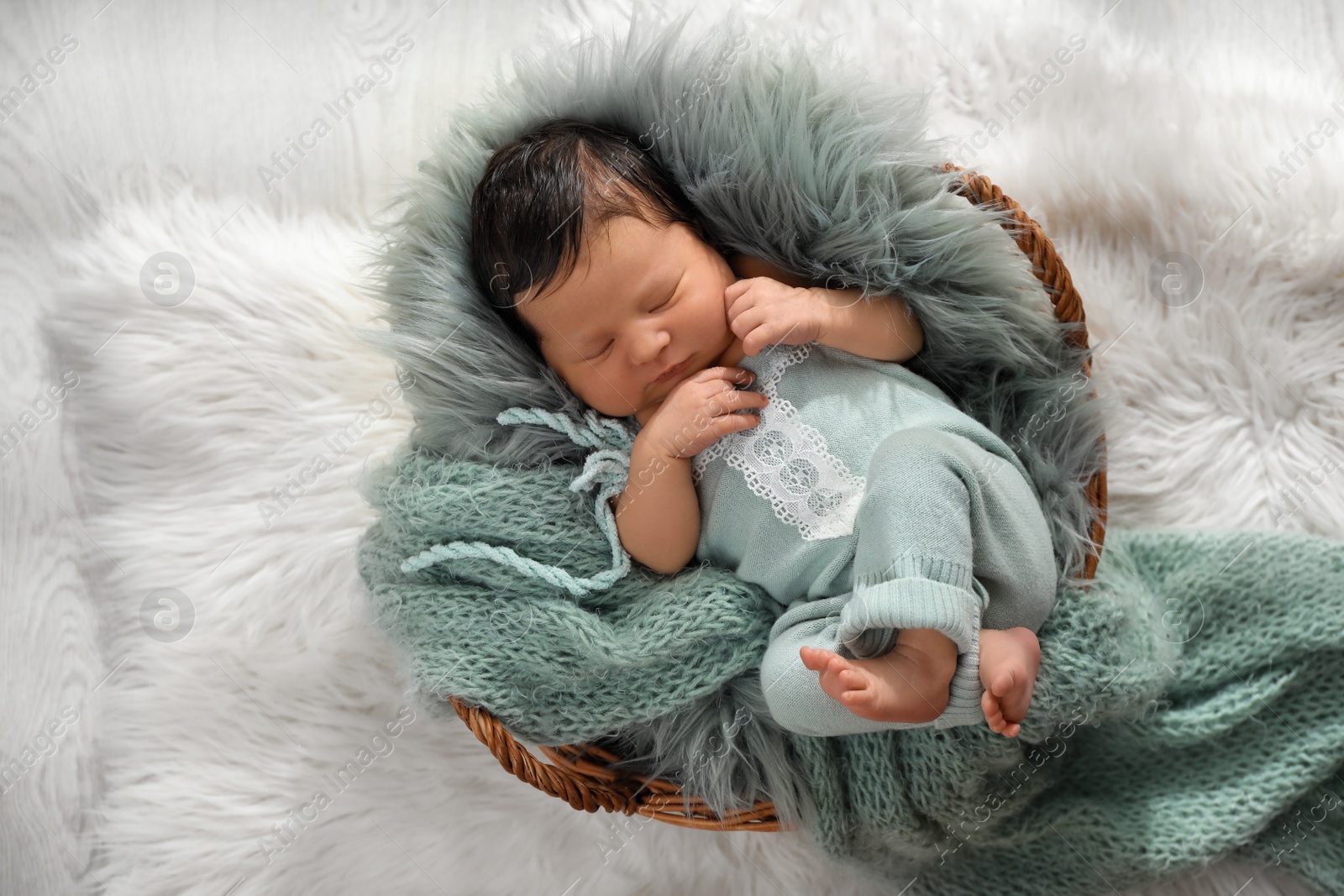 Photo of Cute newborn baby sleeping in wicker basket, top view