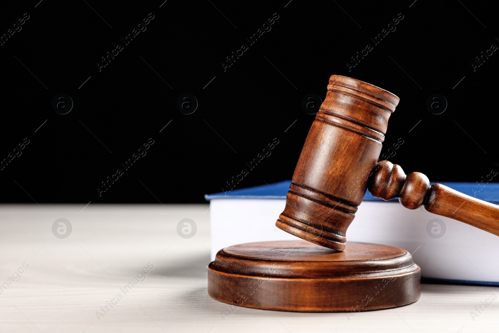 Photo of Judge's gavel and book on white table against black background, space for text. Criminal law concept