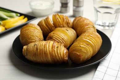 Delicious homemade Hasselback potatoes served on white wooden table