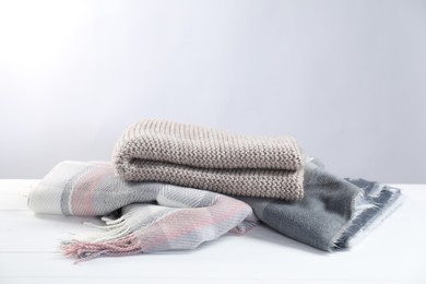 Photo of Stylish soft scarfs on white wooden table, space for text