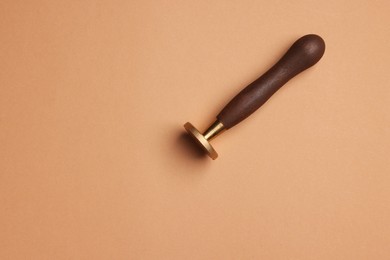One stamp tool with wooden handle on light brown background, top view. Space for text