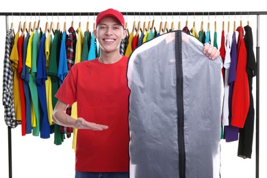 Dry-cleaning delivery. Happy courier holding garment cover with clothes near wardrobe rack on white background