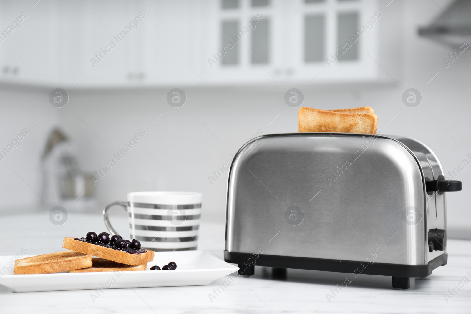 Photo of Modern toaster and tasty breakfast on white table in kitchen
