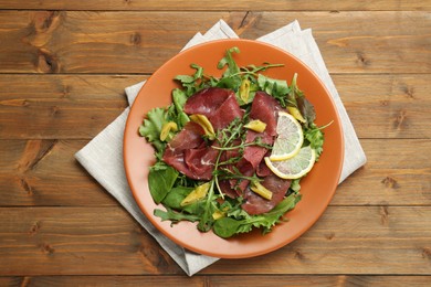 Photo of Delicious bresaola salad on wooden table, top view