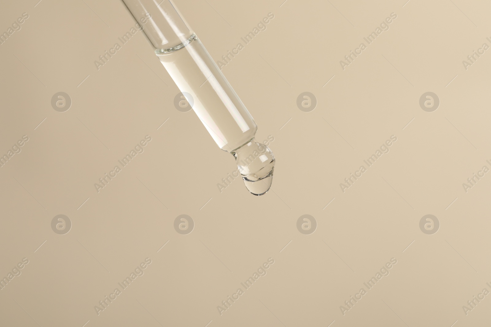 Photo of Dripping cosmetic serum from pipette on beige background, space for text