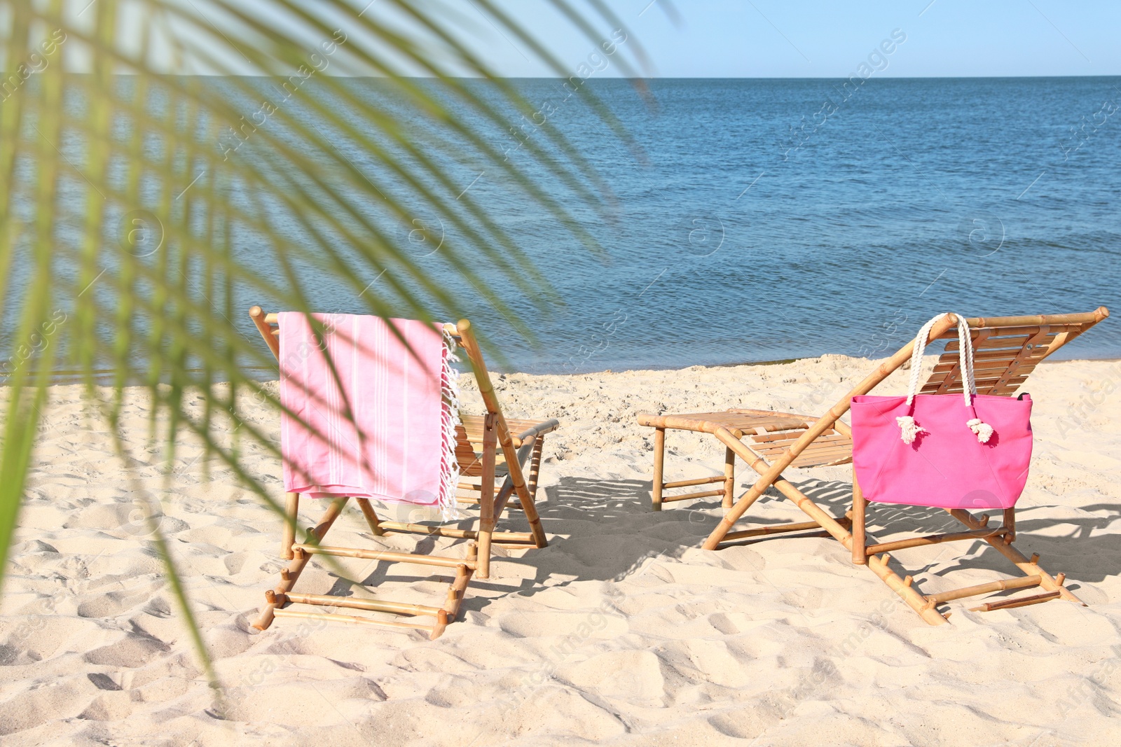 Photo of Empty wooden sunbeds and beach accessories on sandy shore