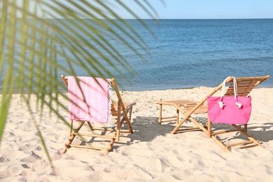 Empty wooden sunbeds and beach accessories on sandy shore