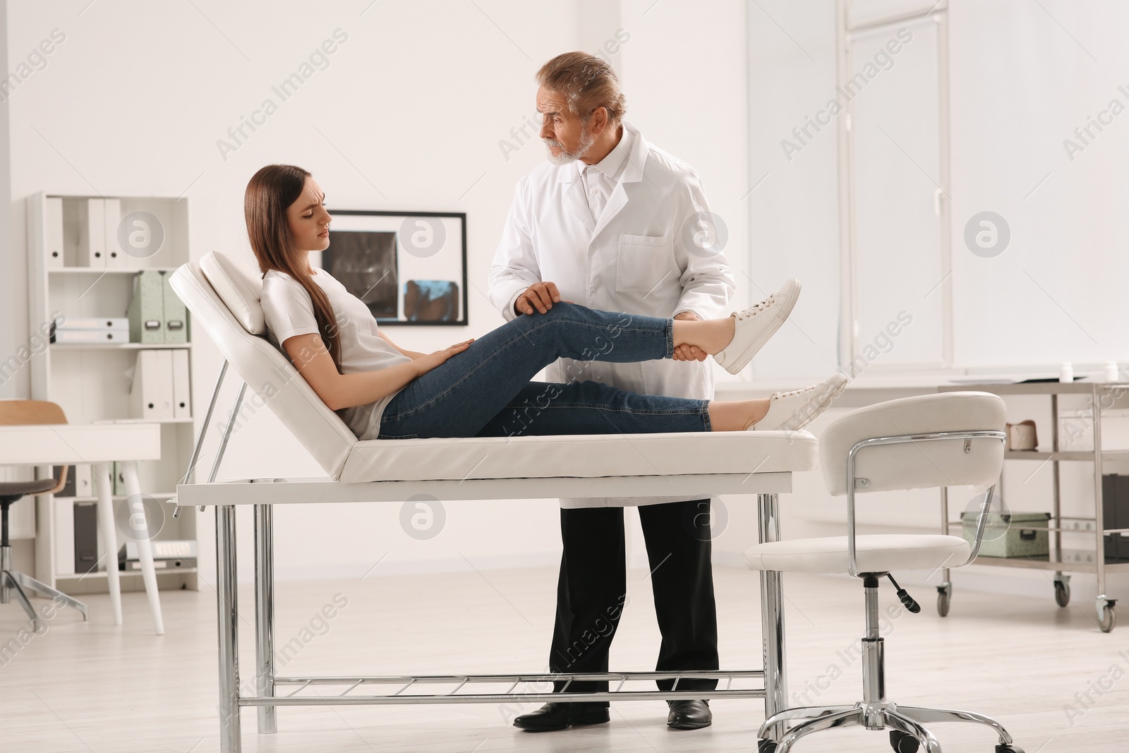 Photo of Orthopedist examining patient with injured knee in clinic