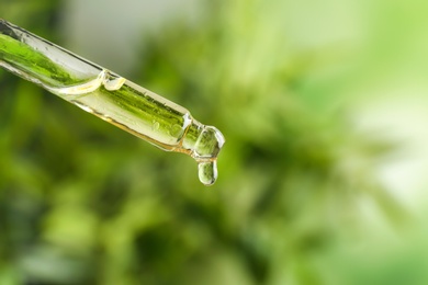 Photo of Dropper with essential oil on blurred background