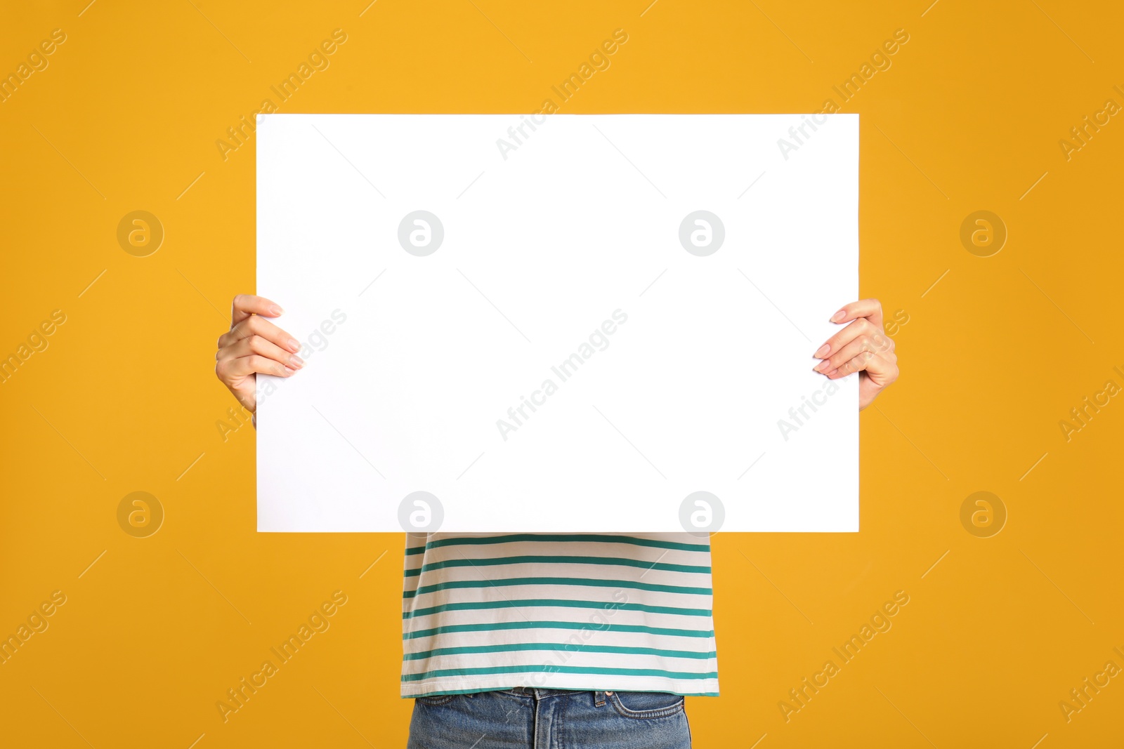 Photo of Woman holding white blank poster on yellow background. Mockup for design